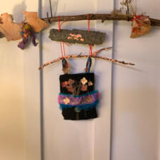 LAURA ROGERS
During this pandemic time I have been painting an oil paint and metal leaf on canvas tree series. When Betsy sent me my seeds she included a beautiful piece of bark and black velvet with small crystal beads that looked like tiny stars. While I was walking my dog found some more bark and branches with lichen. Using the other seeds , copper leaf, painted dried hydrangea flowers and a couple of items from my stash , I made this hanging. I call it “Trees ,Flowers and Stars