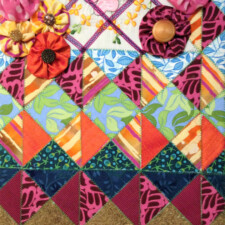 WENDY DUNLEAVY
"Janet's Garden," made from materials I received from Janet Linde, is an 11" x 14" assemblage incorporating handmade paper, woven fabric, buttons, ribbon, and a section of an embroidered handkerchief. You can see everything Janet gave me near the top: the four fabrics in the yo-yos, the selection of buttons, the ribbon, and the handkerchief. The small pieces of cloth were color-related; the challenge in trying to coordinate them was that they were all different types of fabric: silk, cotton, chiffon, and a synthetic. The handkerchief was the most difficult to integrate with the rest of the image because it was on a white ground and seemed to sit on a different plane. Putting it behind the ribbon "trellis" helped de-emphasize the embroidery and created a sense of depth. Overall, I think the visual image would be stronger if the yo-yos were a darker value, but I was determined to get that chiffon in there somehow!